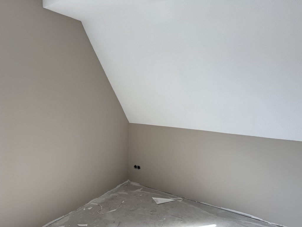 Zolderkamer met schuine wand in een nieuwbouwwoning, klaar voor het vlies