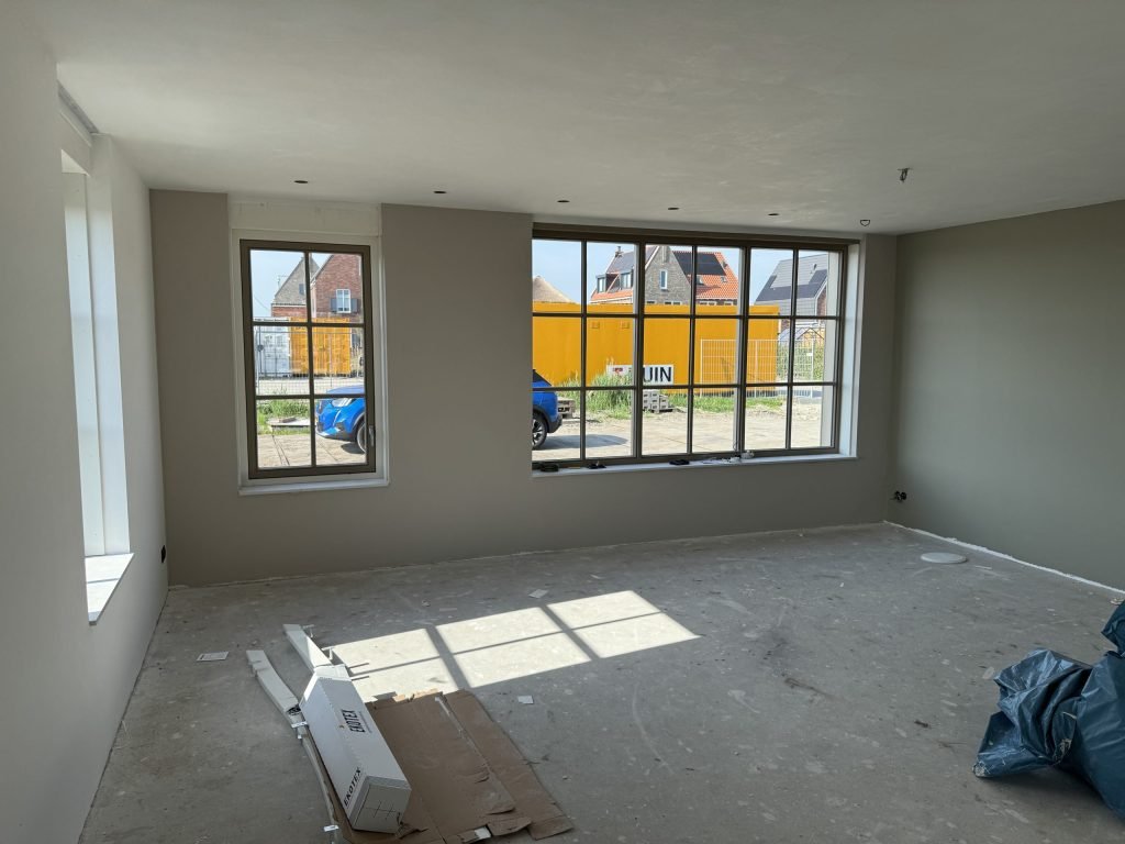 Lege woonkamer van een nieuw huis met roedenramen en egaal geverfde wanden